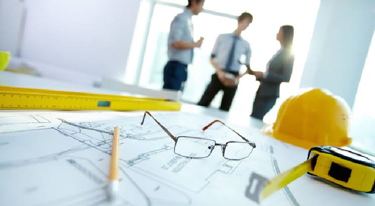 Planos de obra con casco y herramientas de medici&oacute;n